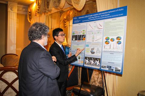 Professor looking at poster while student presents.